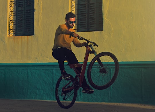 man riding bicycle doing tricks near building photography in Asilah Morocco