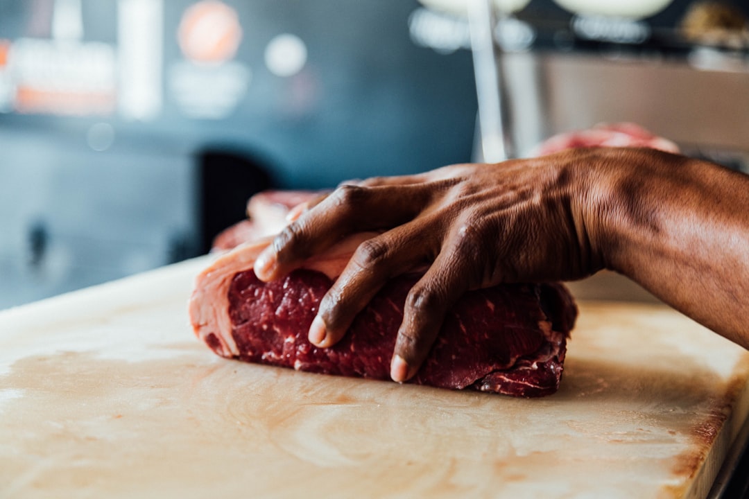 Butcher's hands cut a slab of raw beef