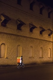A courier carrying a stack of beverage crates on a bike through city streets.