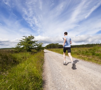 man running on road near grass field