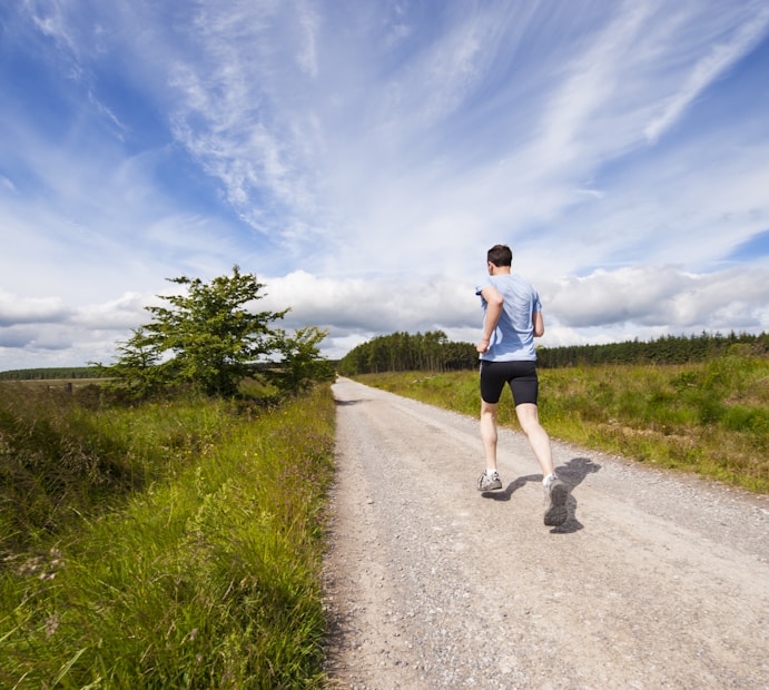 man running on road near grass field