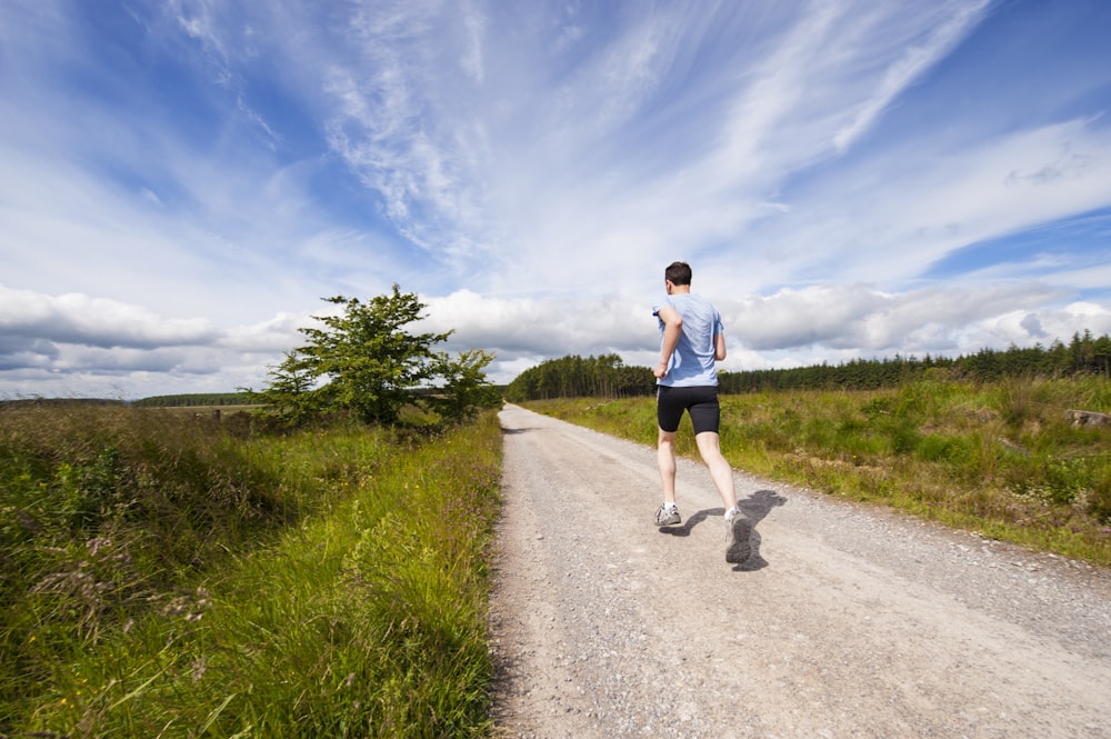 man running on road near grass field