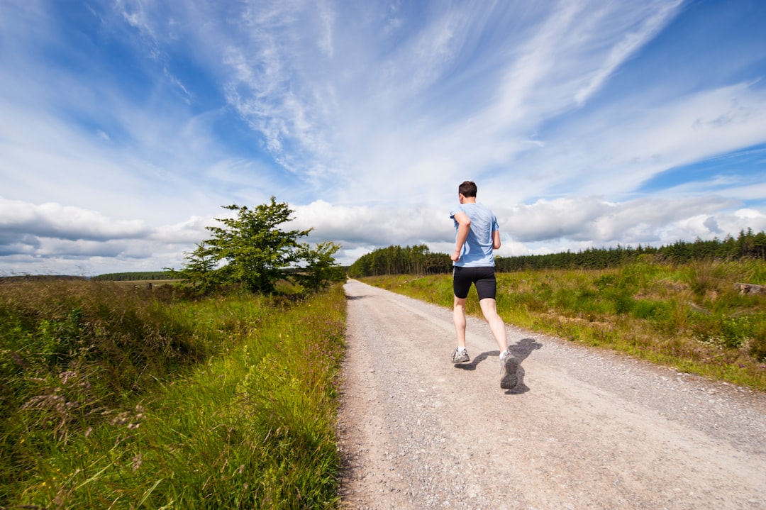 A man running on a dirt path through the grass