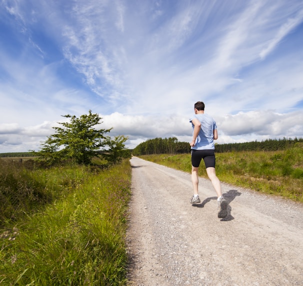 man running on road near grass field