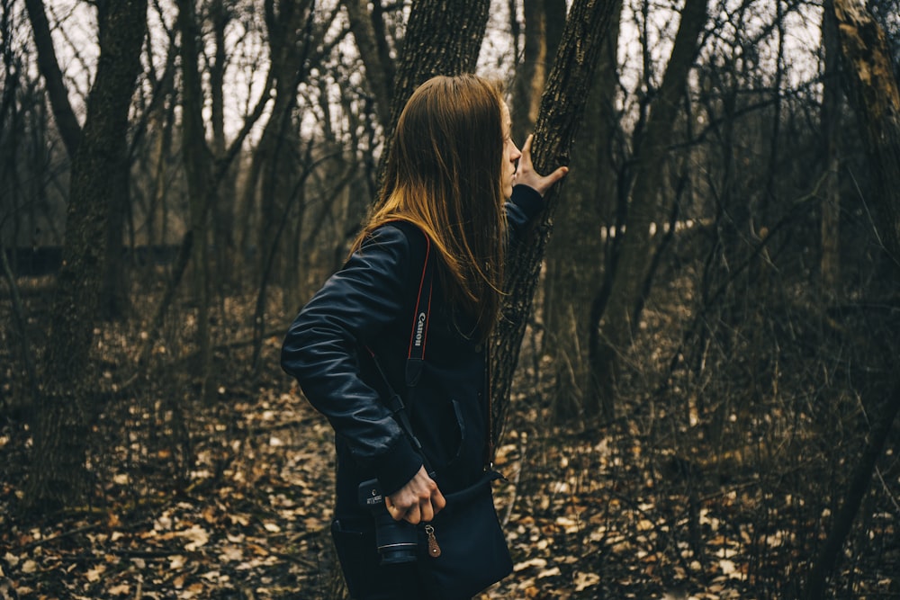 woman in forest holding tree