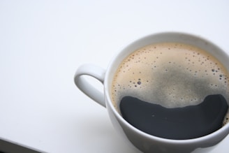 Close-up of a steaming ceramic cup filled with freshly brewed artisan coffee topped with smooth crema.