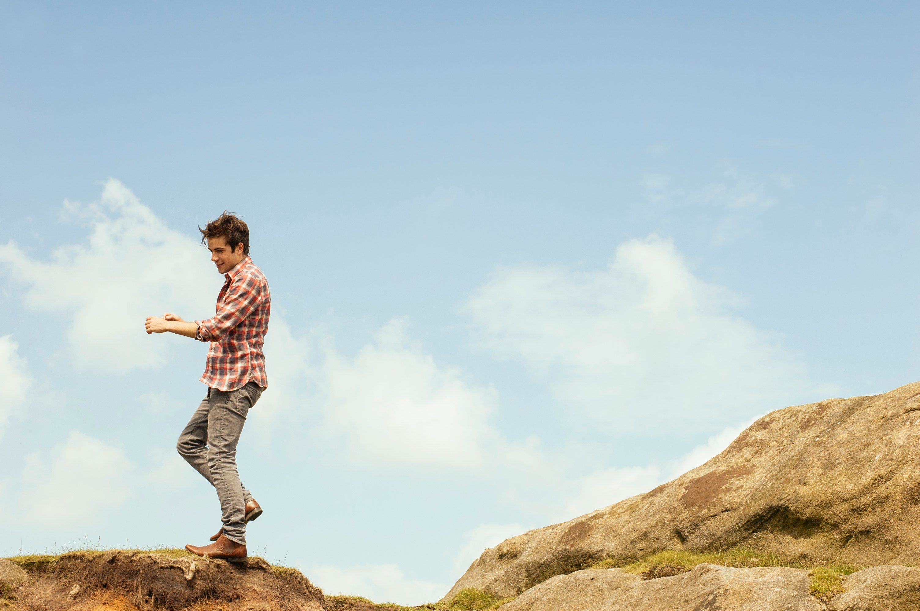 man in red plaid top standing on hilltop during daytime