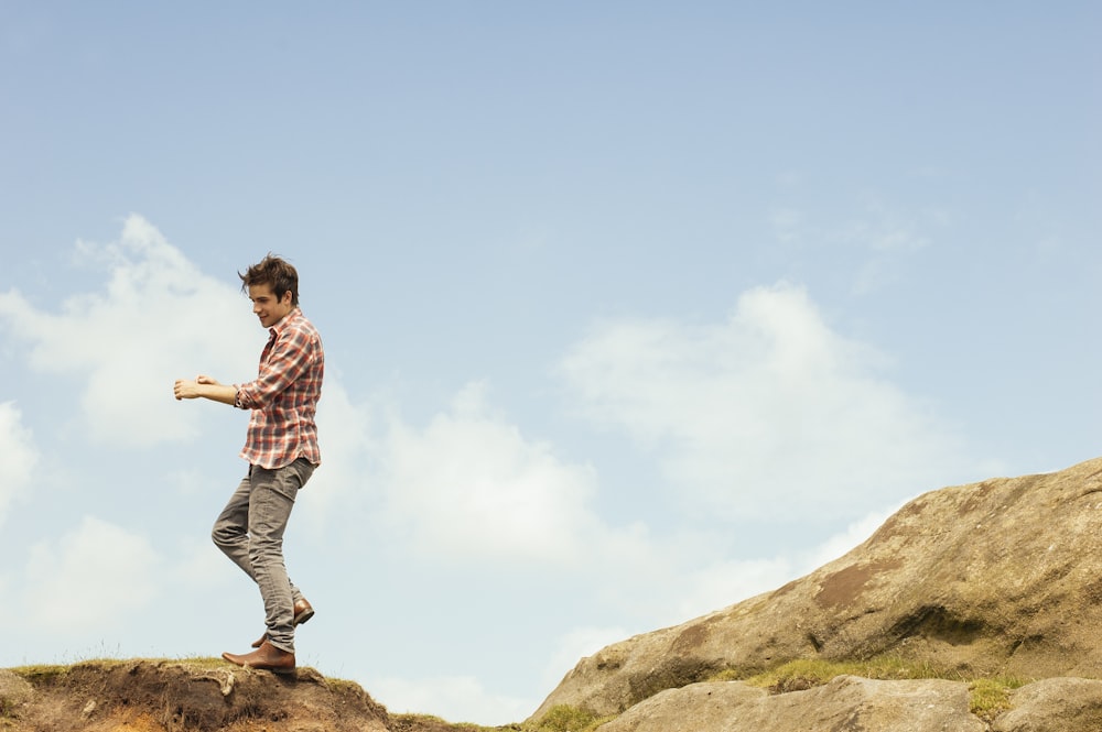 man in red plaid top standing on hilltop during daytime