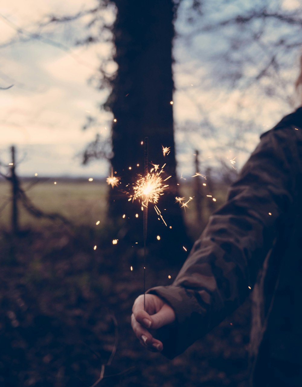 person holding sparkler at daytime