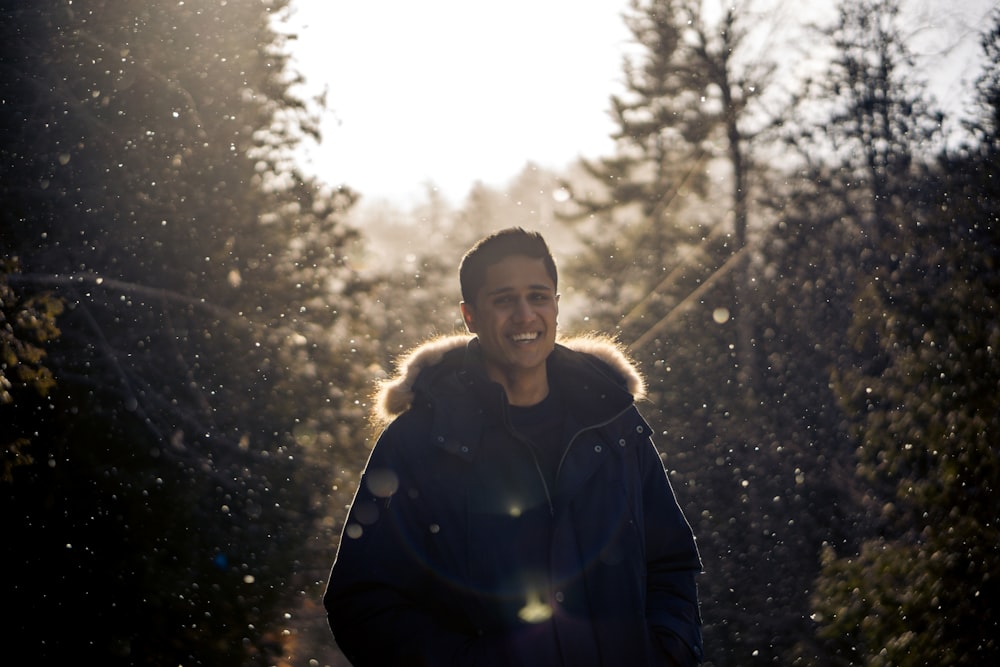 selective focus photo of man standing between pine trees