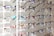 Multiple pairs of eyeglasses arranged neatly on a display rack. The eyeglasses come in various colors and frame styles, and they are evenly spaced and organized in rows.
