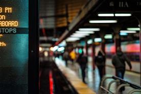 City subway platform lit with signs and commuters walking to their destination