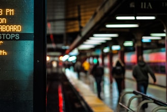 City subway platform lit with signs and commuters walking to their destination