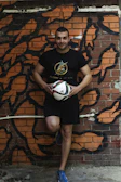 Close-up of a football creator filming himself juggling a ball against a graffiti wall.