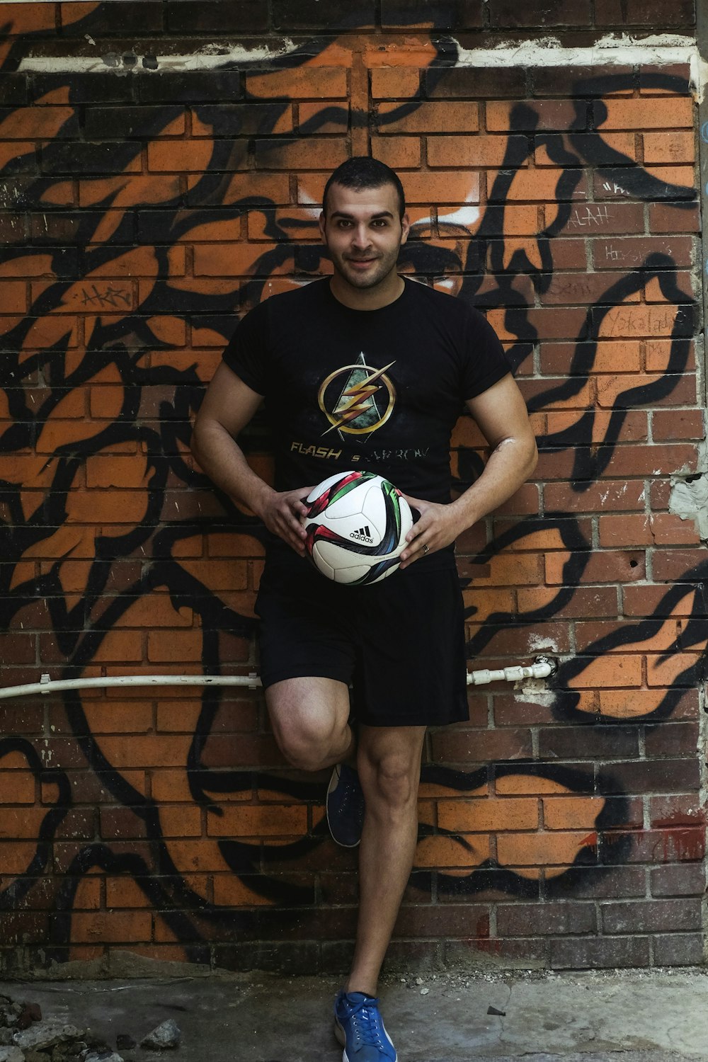 man leaning on wall holding velleyball