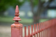 Close-up of a sleek metal fence post anchored firmly into a stone base near a driveway.