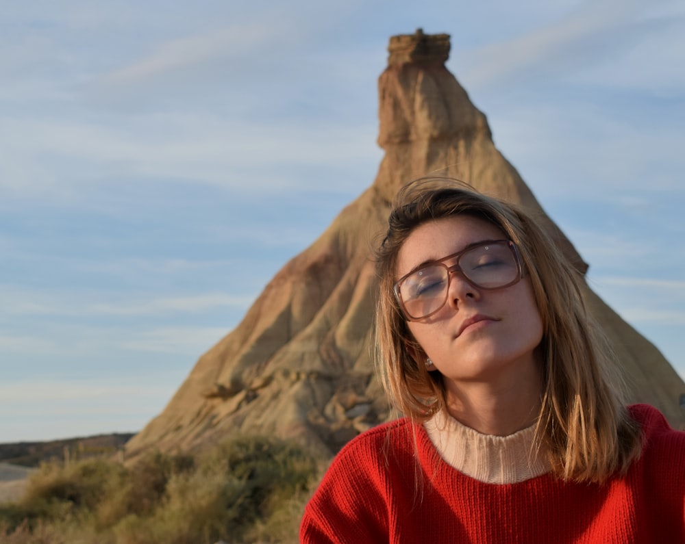 woman with sunglasses taking photo in front of rock formation during daytime