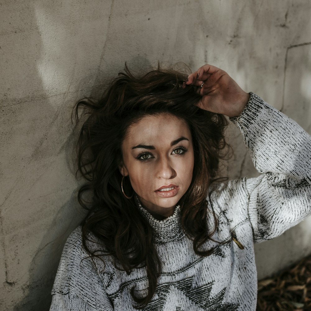 focus photography of woman with left hand on her head while leaning against wall