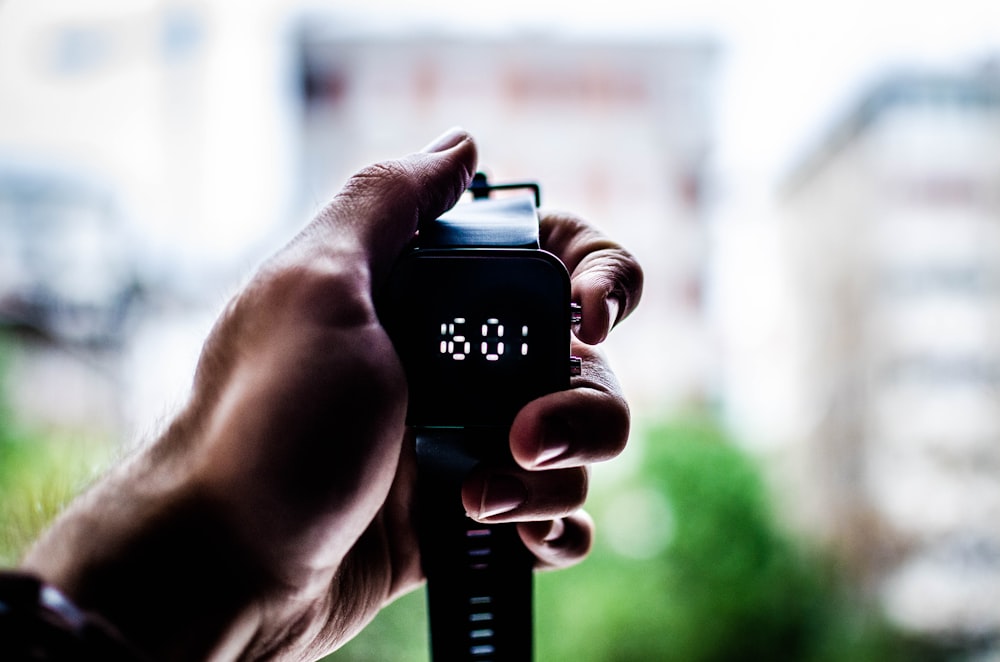 person holding digital watch