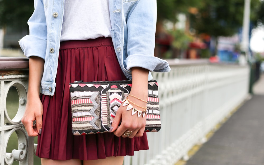 woman holding clutch bag standing beside white bridge