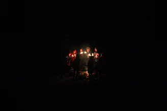 A circle of people holding hands in a cozy room lit by soft candles, creating a warm and inviting atmosphere.