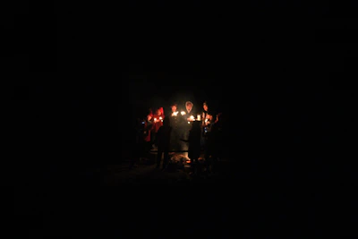 A warm community circle holding lit candles during a reflective faith gathering.