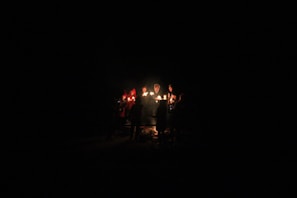 A group seated in a circle, faces illuminated by candlelight, immersed in a shared moment of presence