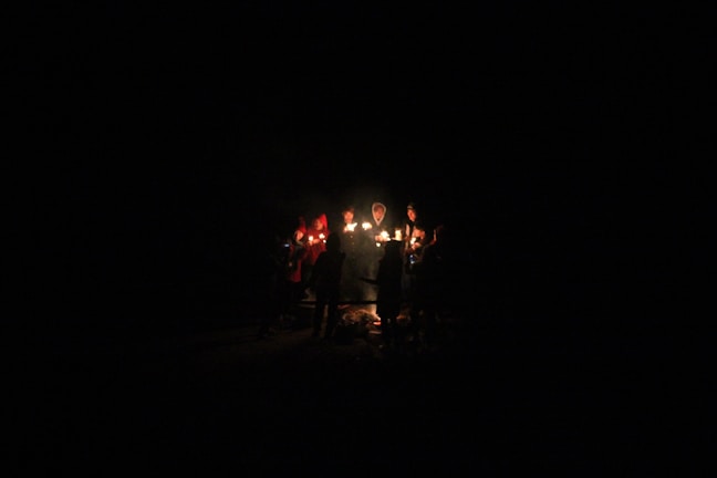 A group of diverse individuals holding candles in unity.