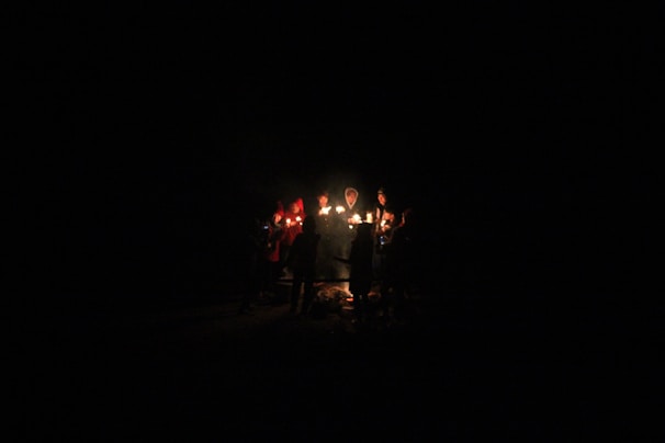 A warm gathering of people sitting in a circle, illuminated by soft candlelight indoors.
