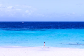 A lone traveler standing on a pristine white sand beach, gazing at the turquoise waves of a hidden Philippine island.