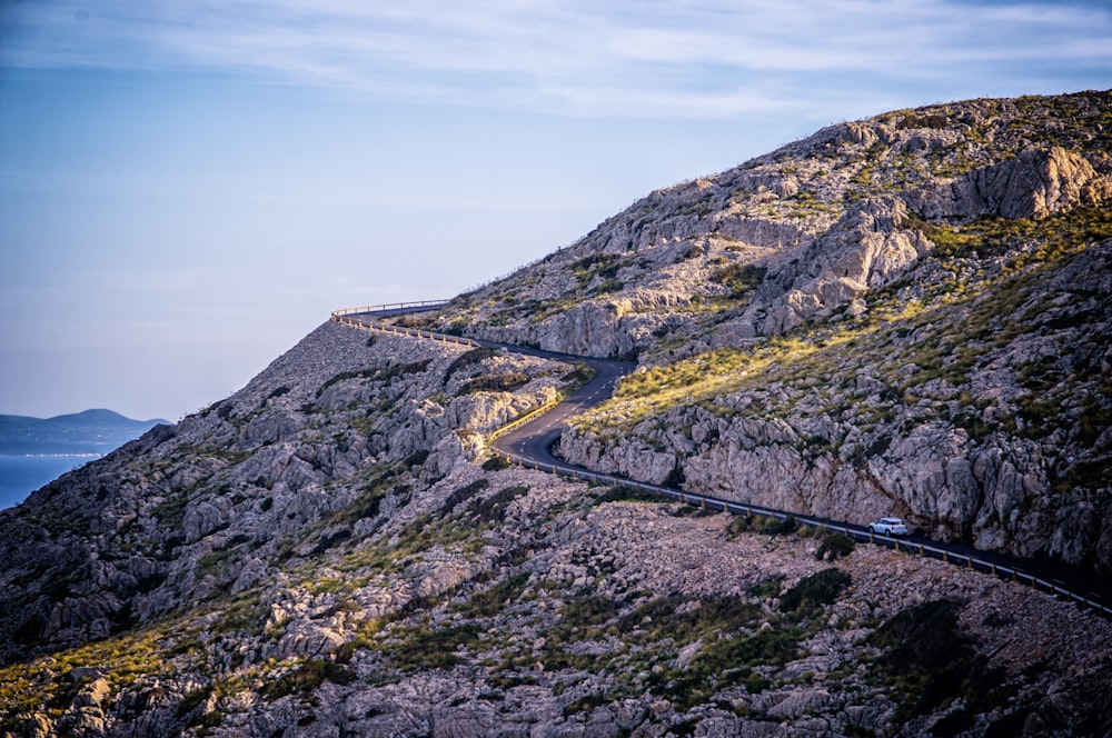 white car traveling on road near mountain