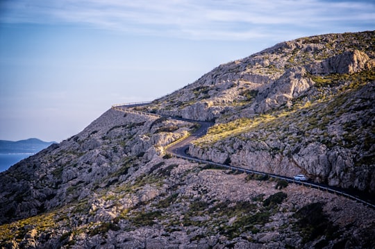 white car traveling on road near mountain in Cap de Formentor Spain