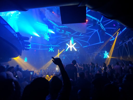 A lively 90s-themed nightclub interior with colorful lights and dancing crowd.