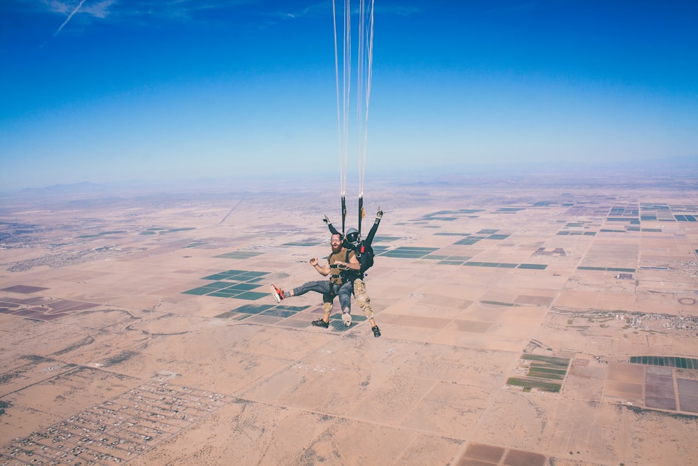 two men in 1 parachute in mid air during daytime