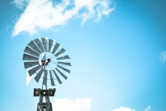 A vibrant metal wind spinner catching the Aegean breeze against a clear blue sky.