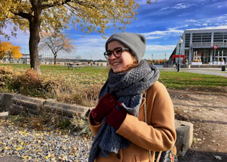 A smiling woman wearing a faux cashmere scarf outdoors on a crisp autumn day.