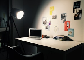 Sleek desk lamp highlighting a workspace with books and a laptop.