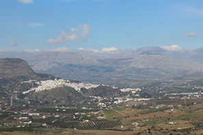 A panoramic view of El Cabaco village nestled in the Sierra de Francia, with lush green hills and clear blue sky.