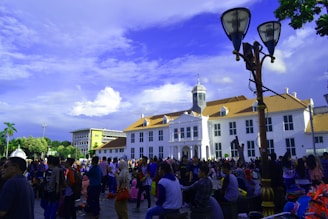 A bustling plaza entrance with colorful banners and happy visitors enjoying the sunny day.
