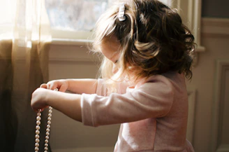 A joyful child holding a rosary with sunlight filtering through church windows.