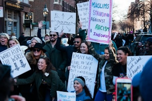 A group of diverse volunteers smiling and holding event signs outdoors.