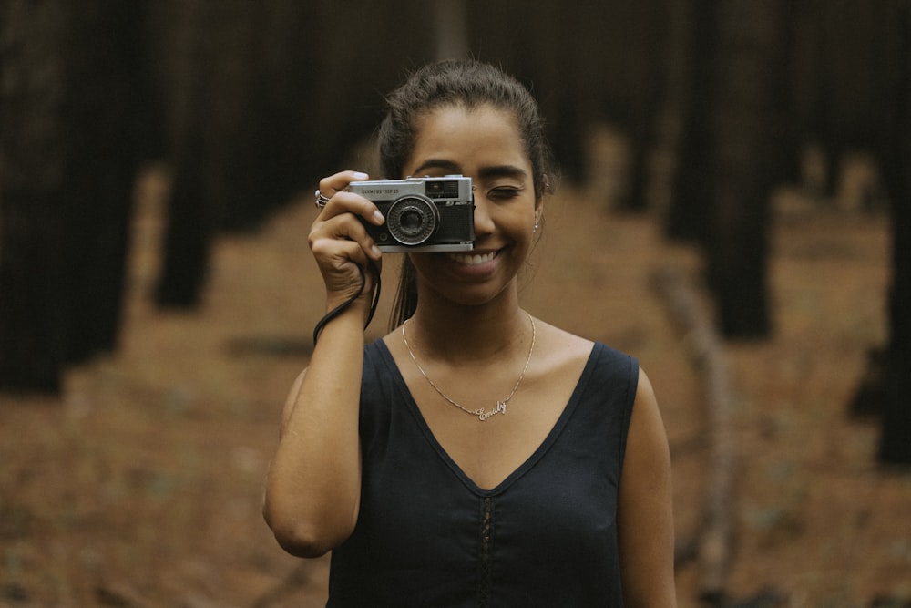 femme tenant un appareil photo reflex numérique argenté pendant la journée