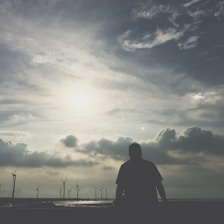 Portrait of Adil Smaili smiling confidently against a backdrop of solar panels and wind turbines.