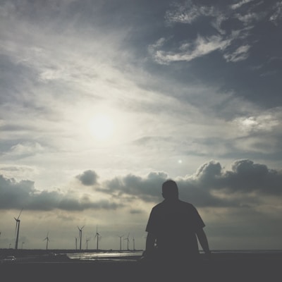 Portrait of Adil Smaili smiling confidently against a backdrop of solar panels and wind turbines.
