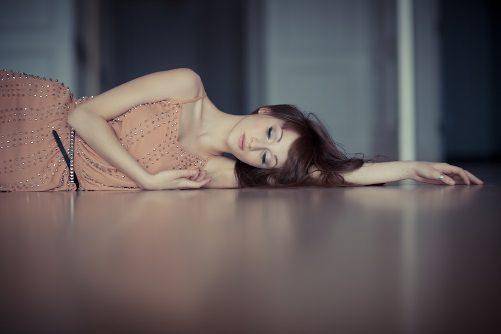 woman wearing pink dress lying on cement