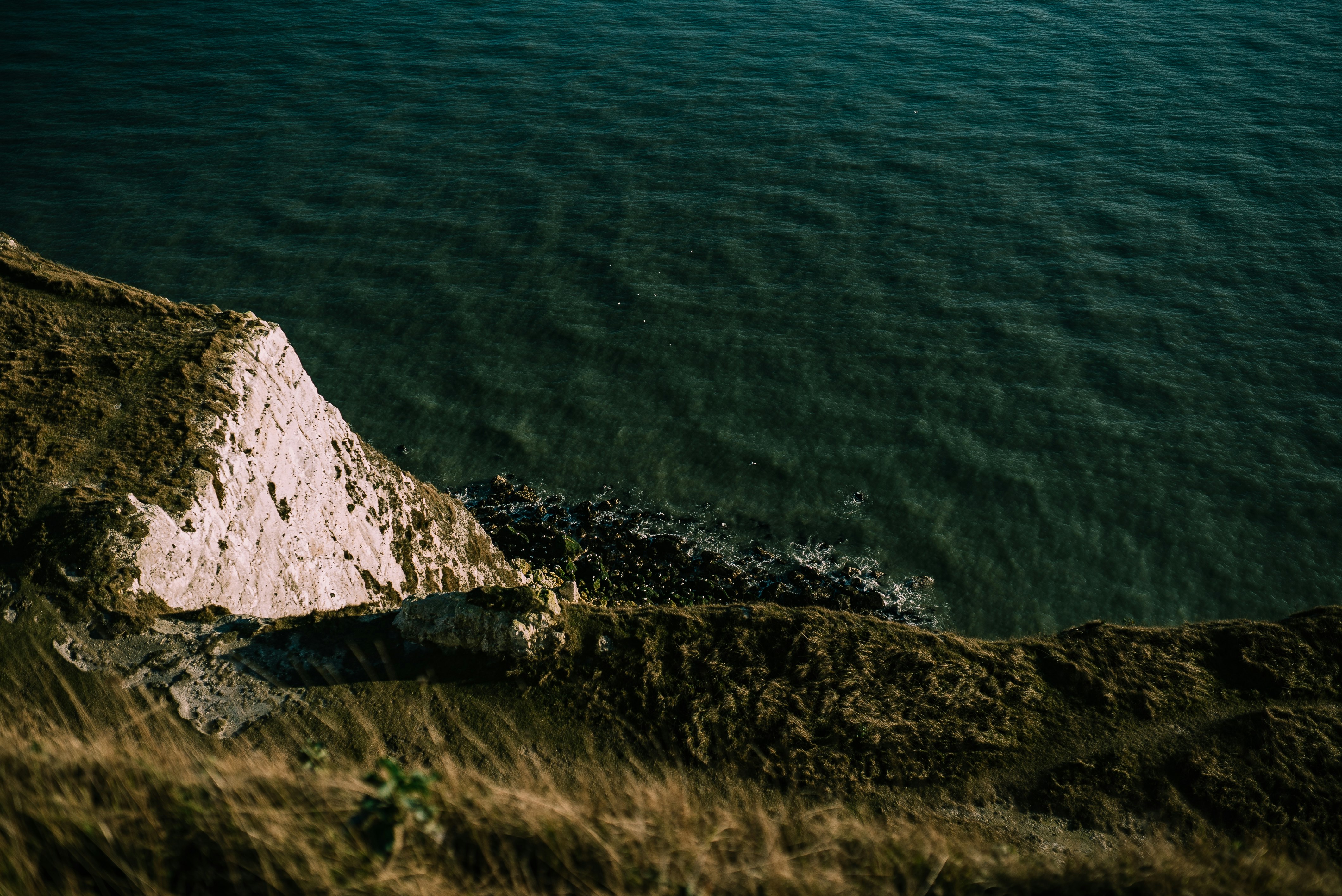 green grass cliff beside green body of water