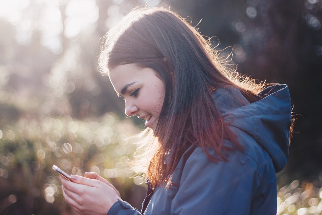 woman holding phone smiling, Woman smiling at a smartphone