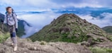A scenic mountain trail with a hiker pausing to admire the view, budget gear visible.