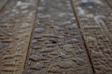 Drops of water scattered across a wooden surface, highlighting the wood grain texture. The surface appears wet with varying sizes of water droplets.