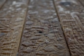 Drops of water scattered across a wooden surface, highlighting the wood grain texture. The surface appears wet with varying sizes of water droplets.